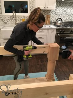 a woman is working on some wood in the kitchen with her drill and cordless tool