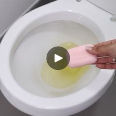 a person is using an electric toothbrush to clean a white toilet with yellow liquid