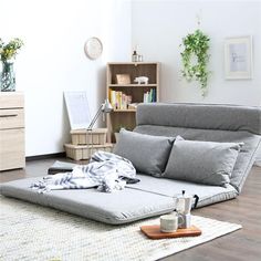 a living room filled with furniture and lots of pillows on top of a floor next to a book shelf