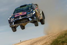 a car is flying through the air with its wheels in the air as it goes over a dirt road