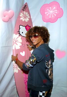 a woman standing next to a pink surfboard with hello kitty on it's side