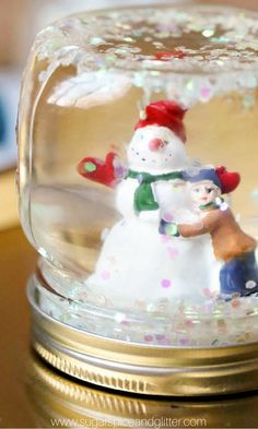 a snowman and dog in a glass dome on top of a table with confetti sprinkles