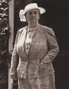 an old woman wearing a suit and hat