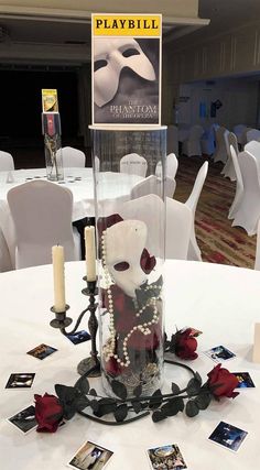 a table topped with a vase filled with flowers and candles next to a sign that says playbill