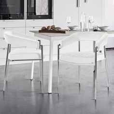 two white chairs sitting at a table in a kitchen