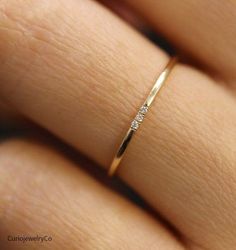 a woman's hand with a diamond ring on her left hand, and the other hand is wearing a yellow gold band