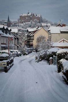 a snow covered street with houses and buildings in the background