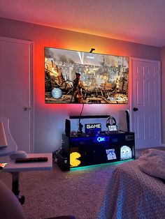 a bedroom with a large flat screen tv mounted above it's headboard and video game controllers on the floor