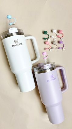 two travel mugs, one with an insulated lid and the other with earbuds