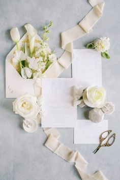 the wedding stationery is laid out with flowers and ribbon