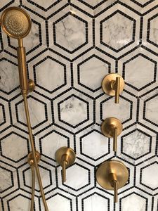 a bathroom with gold fixtures and hexagonal tiles