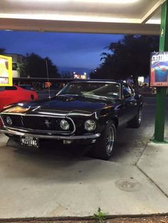 an old mustang parked in a gas station