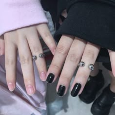 two women with black fingernails and rings on their fingers