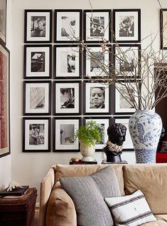 a living room with pictures on the wall and vases filled with flowers in it