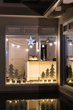 a kitchen with christmas lights on the windows and trees cut out of glass in front of it