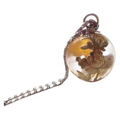 a necklace with a glass ball and flowers on it