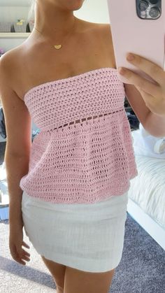 a woman is taking a selfie with her cell phone while wearing a pink crochet top