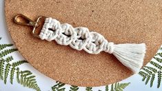 a white crochet keychain with a tassel hanging from it on a cork board