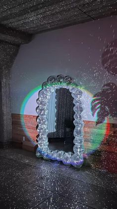 a mirror that is sitting on the floor in front of a wall with light coming from it