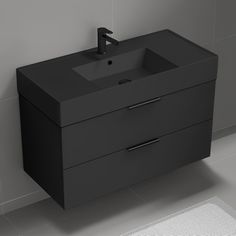 a bathroom sink sitting next to a wall mounted faucet on a tiled floor