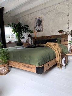 a bedroom with a bed, plant and pictures on the wall