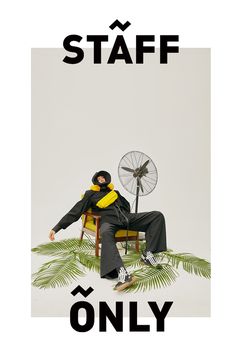 a man sitting in a chair next to a fan on top of a palm tree