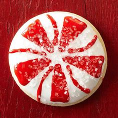 a red and white cake sitting on top of a wooden table covered in icing