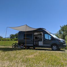 an rv parked in the middle of a field with a tent on it's roof