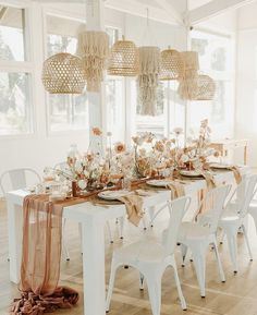 a dining room table set with white chairs and an orange runner on top of it