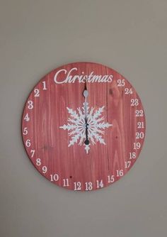 a red clock with white snowflakes on it and the words christmas written in cursive writing