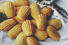 a pile of cookies sitting on top of a white napkin next to a sprig of rosemary