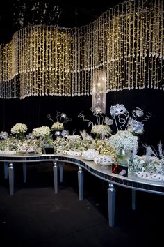 a table topped with lots of white flowers next to a chandelier filled with lights