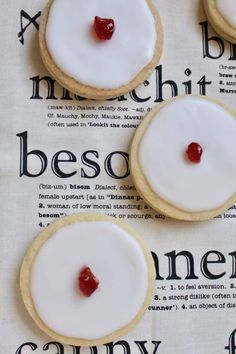 three cookies with white icing and cherries on top of a tablecloth that says bescod