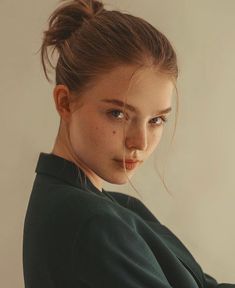 a young woman with freckled hair is posing for the camera while wearing a green sweater