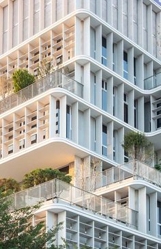 an apartment building with balconies and trees on the top floor is white in color