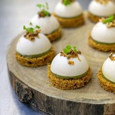 several small desserts are arranged on a wooden platter with green garnishes