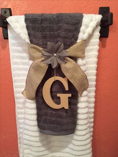 a towel hanging on the wall with a letter g in it and a bow at the top