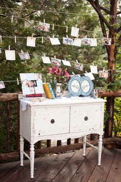 an old dresser is decorated with photos and pictures on clothes pins strung from the line