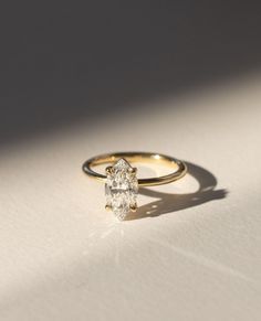 a yellow gold ring with a single diamond on the top, sitting on a white surface