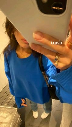 a woman taking a selfie with her cell phone in front of her face and wearing a blue sweater