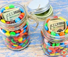 two jars filled with candy and money on top of a blue wooden table next to each other