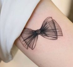 a woman's arm with a bow tattoo on the left side of her arm