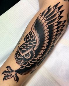 a black and white owl tattoo on the arm