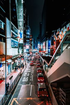 a city street filled with lots of traffic and tall buildings in the background at night