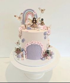 a cake decorated with fairy figurines sitting on top of a table