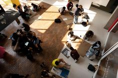 an overhead view of people sitting on the floor and standing around in a room with large windows