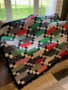 a black and white checkered quilt sitting on top of a wooden floor next to a window