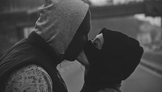 two people are standing close to each other and one is wearing a hood on his head