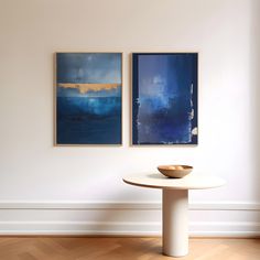 two paintings hang on the wall next to a table with a bowl in front of it