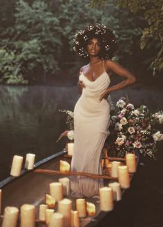 a woman in a white dress is standing on a boat with candles around her waist